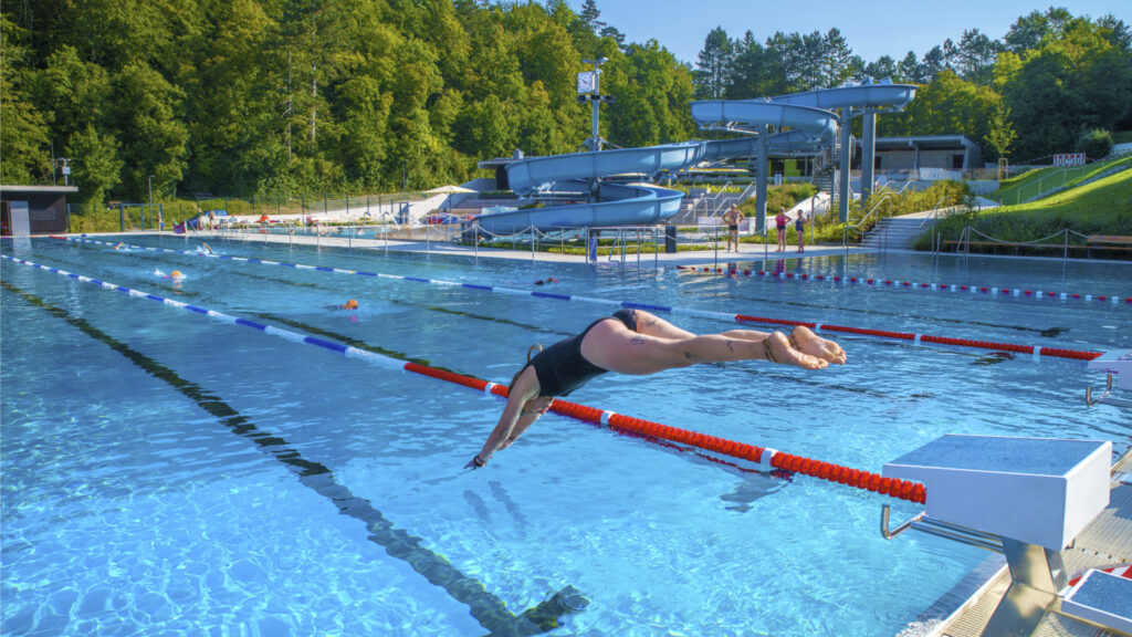 Schwimmerin springt vom Startblock ins Wasser