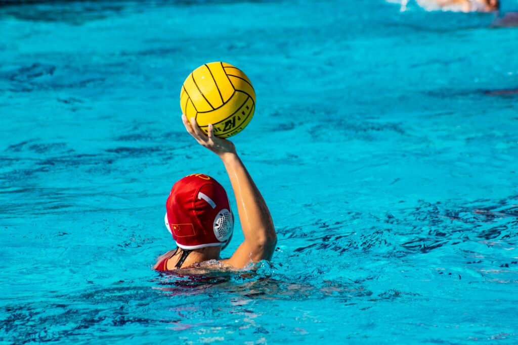Person, Ansicht von hinten, wirft Wasserball im Wasser